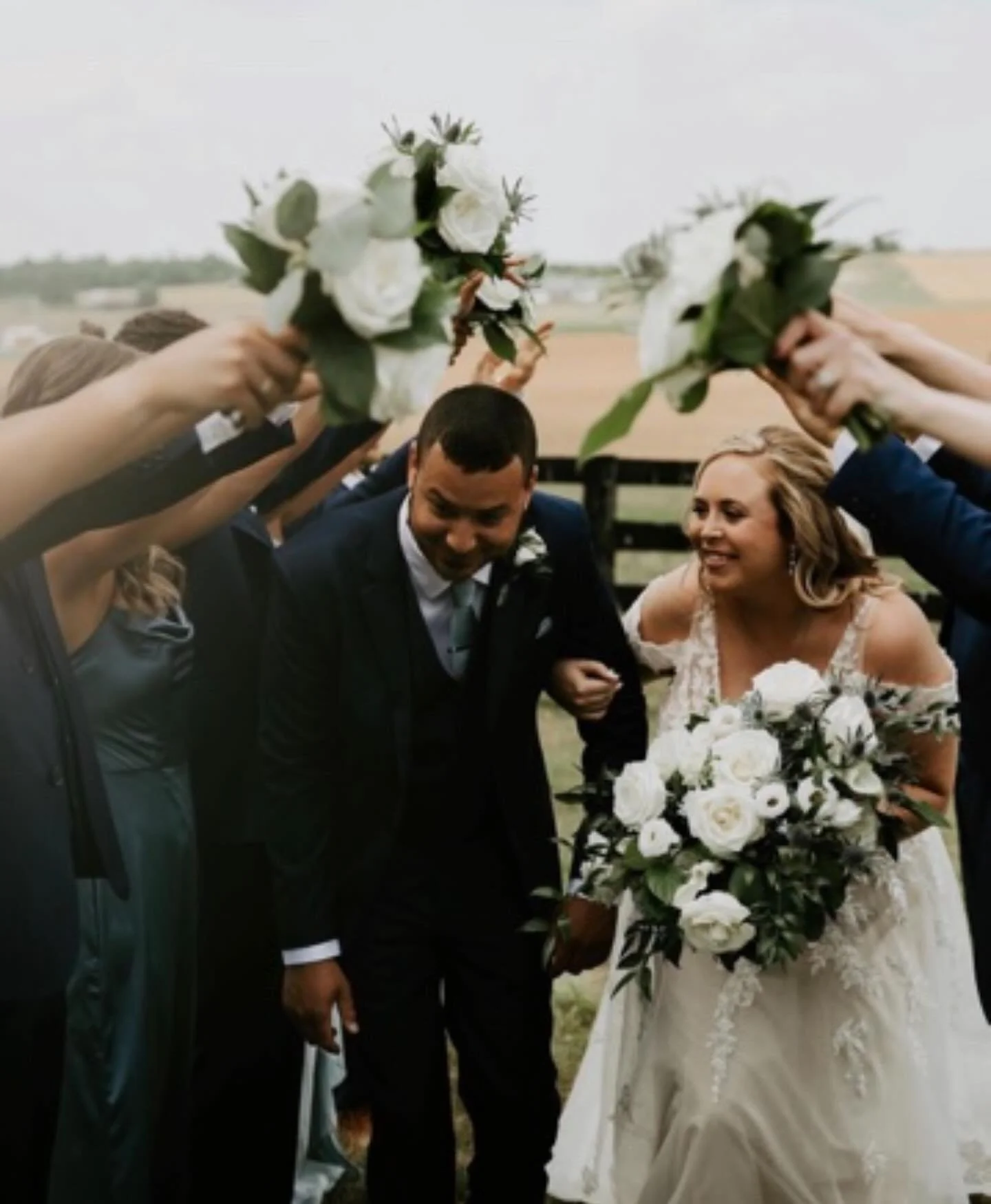 Wedding party raising bouquets over the newlyweds